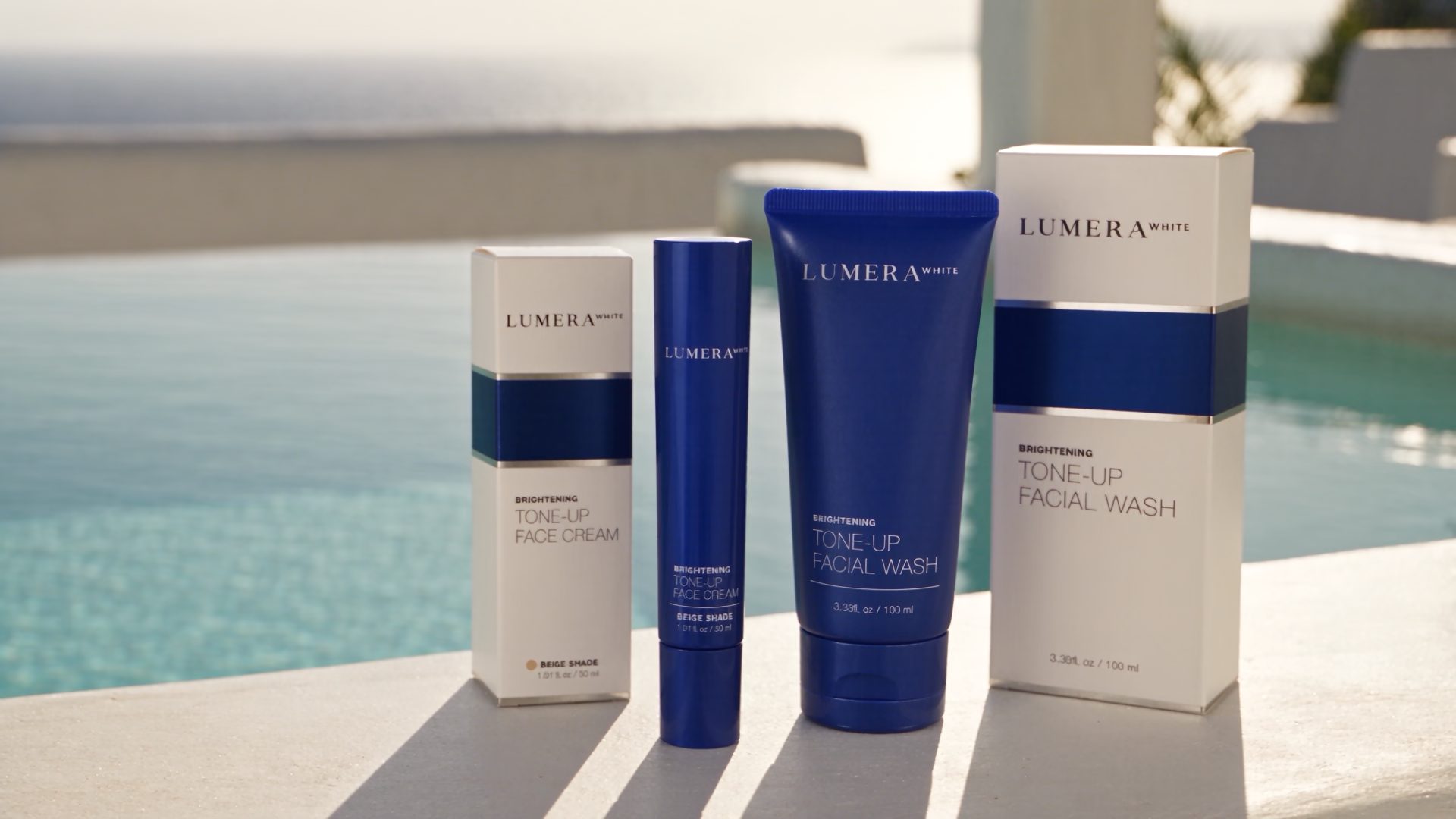 Lumera Tone-Up Face Cream and Tone-Up Facial Wash with their cartons on a sunlit poolside ledge